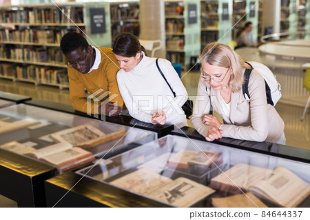 Professor and adult students read ancient books in a library showcase 84644337