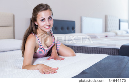 Sexy smiling woman lying and touching mattress Sexy smiling woman lying and touching mattress 84644370