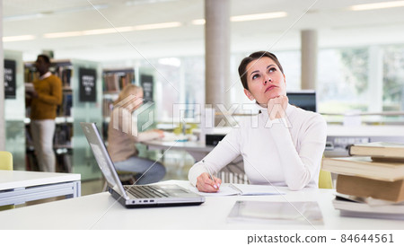 Portrait of upset tired female student preparing for exam in university library Portrait of upset tired female student preparing for exam in university library 84644561