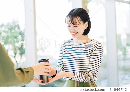 A woman taking out coffee with a tumbler 84644742