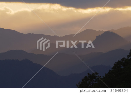 Beautiful sunset view of the Kii Mountains where the setting sun shines [From the World Heritage Kumano Kodo Tsuzurato Pass] 84649894