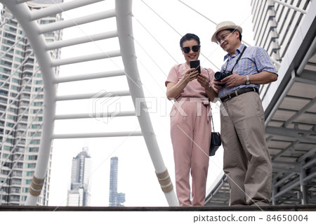 Senior Asian couple playing mobile outdoors. Senior Asian couple playing mobile outdoors. 84650004