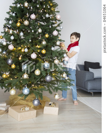 Boy with gifts plays near the Christmas tree Boy with gifts plays near the Christmas tree 84651064