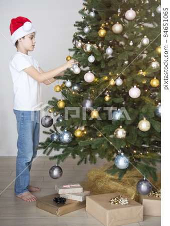 Boy with gifts plays near the Christmas tree Boy with gifts plays near the Christmas tree 84651065