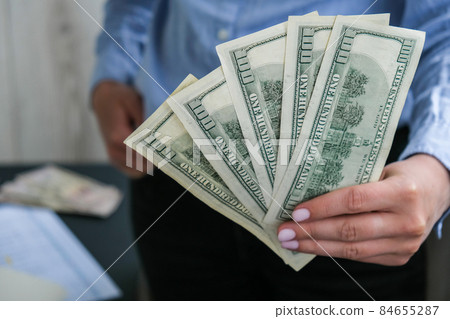 Business Woman Displaying a Spread of Cash US dollars. Close-up. Income and Business concept. Venality, bribe, corruption concept. Hand giving money. Millennial candid authentic female hands counting 84655287