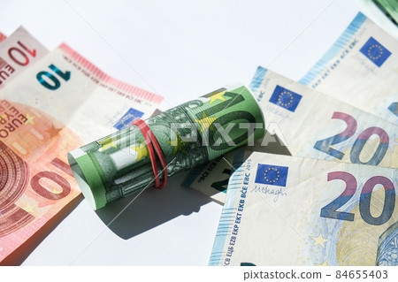 Close up of Euro money roll. Euro banknote set cash money - EU currency. Rolled with rubber euro notes. Banknotes stacked on each other in different positions Close up of Euro money roll. Euro banknote set cash money - EU currency. Rolled with rubber euro notes. Banknotes stacked on each other in different positions 84655403