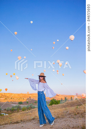 Happy woman during sunrise watching hot air balloons in Cappadocia, Turkey 84655693