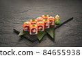 sushi rolls with tuna salmon eel unagi and avocado on a black stone plate. 84655938