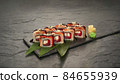 sushi rolls with tuna salmon eel unagi and avocado on a black stone plate. 84655939