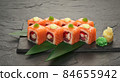 sushi rolls with tuna salmon eel unagi and avocado on a black stone plate. 84655942