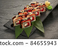 sushi rolls with tuna salmon eel unagi and avocado on a black stone plate. 84655943