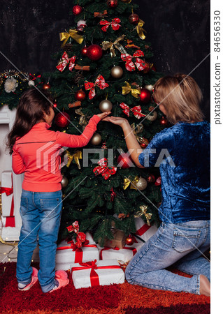 mom and little girl decorate christmas tree toys new year 84656330