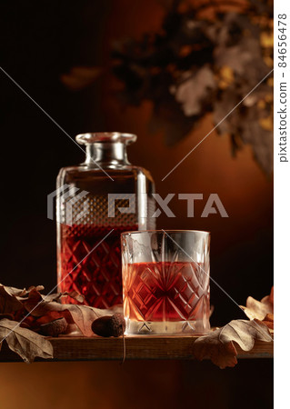 Whiskey on a wooden table with dried-up oak leaves. Whiskey on a wooden table with dried-up oak leaves. 84656478