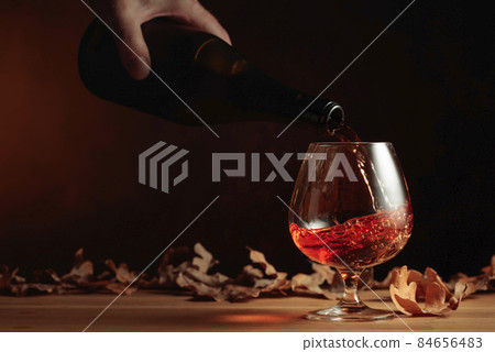 Brandy is poured from a bottle into a glass. 84656483