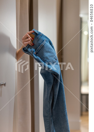 The customer in the fitting room returns to the consultant trousers that did not fit in size. The customer in the fitting room returns to the consultant trousers that did not fit in size. 84656810