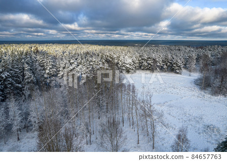 Aerial view of frosty white winter pine forests and birch groves covered with hoarfrost and snow. Drone photo of high trees in mountains at winter time. Christmas theme background. Idyllic landscape Aerial view of frosty white winter pine forests and birch groves covered with hoarfrost and snow. Drone photo of high trees in mountains at winter time. Christmas theme background. Idyllic landscape 84657763