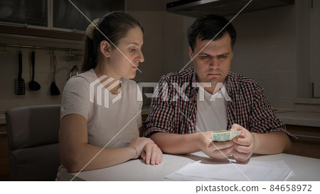 Young couple having to pay monthly payment counting few money they have left Young couple having to pay monthly payment counting few money they have left 84658972