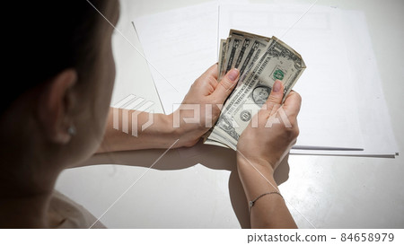 CLoseup of young woman having financial diffuculties counting her money behind kitchen table CLoseup of young woman having financial diffuculties counting her money behind kitchen table 84658979
