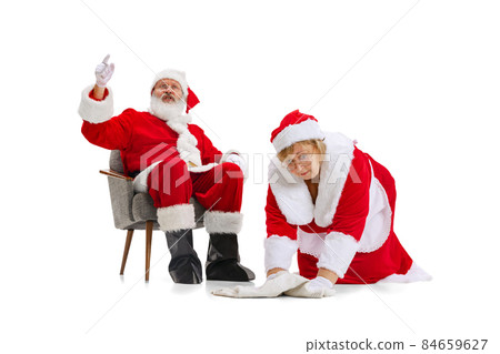 Senior man and beautiful middle-aged woman, Santa Claus and missis Claus in traditional New Year costume isolated on white background. 84659627