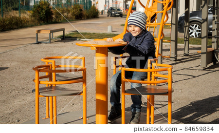 Little boy riding and spinning on carousel at courtyard playground. Concept of child development, sports and education. 84659834