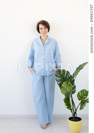 Young attractive woman dressed in beautiful colorful pajama posing as a model in her living room. Comfortable sleepwear, home relaxation and female fashion concept. Young attractive woman dressed in beautiful colorful pajama posing as a model in her living room. Comfortable sleepwear, home relaxation and female fashion concept. 84661597