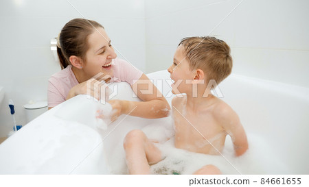Portrait of happy mother smiing at her little son washing in bath at home Portrait of happy mother smiing at her little son washing in bath at home 84661655
