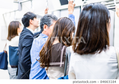 Business person commuting on a crowded train Business person commuting on a crowded train 84663184