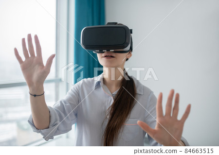 Female gamer in VR glasses standing in a room 84663515