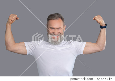 A mature man in a white tshirt showing his muscles 84663716