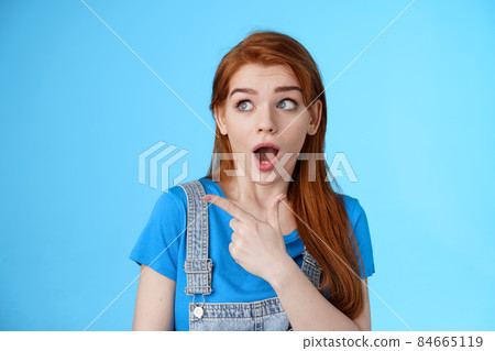 Surprised speechless ginger girl react shocked interested awesome copy space price fall, drop jaw pointing looking stunned left, open mouth fasinated amazed, stand blue background astonished Surprised speechless ginger girl react shocked interested awesome copy space price fall, drop jaw pointing looking stunned left, open mouth fasinated amazed, stand blue background astonished 84665119
