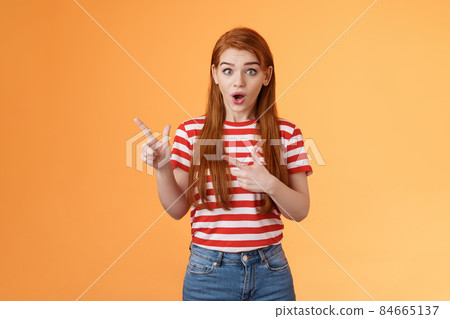Wow awesome. Impressed excited beautiful redhead woman look astonished explain amazing news, stare camera thrilled talking about advertisement, pointing left upbeat impressed, orange background 84665137