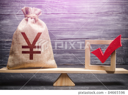 Red vote tick and a chinese yuan or japanese yen money bag on scales. Concept of lobbying for decisions and laws. Estimating cost of making a decision and consequences in the future. Corruption risks. 84665596
