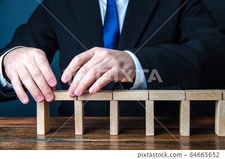 A man building a bridge of domino blocks. Strategy planning business expansion. Development and progression. Leadership. Create, design, expand a company. A stable foundation movement towards the goal 84665652