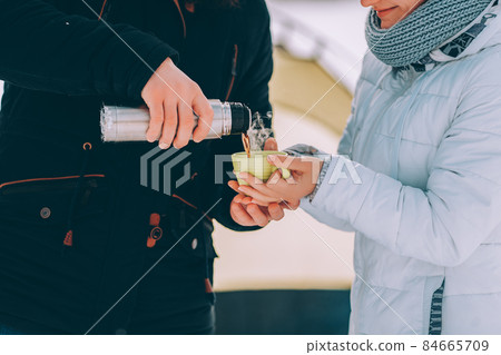 guy pour hot coffee to his girlfriend in green cup. winter hike theme 84665709
