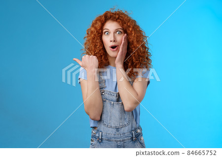 Omg how intriguing. Impressed charismatic emotive surprised redhead cute curly girl open mouth gasping curious amazed touch cheek silly pointing left thumb telling about astonishing store 84665752