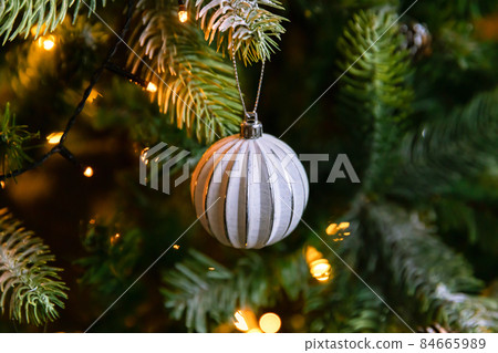 Classic Christmas decorated New year tree. Christmas tree with wite and silver decorations, ornaments toy and ball. Modern classical style interior design apartment. Christmas eve at home 84665989
