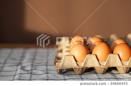 Few brown eggs among the cells of a large cardboard bag, chicken egg as a valuable nutritious product, a tray for carrying and storing fragile eggs. Not a full package of eggs, an important food item 84666455