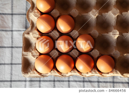 Few brown eggs among the cells of a large cardboard bag, chicken egg as a valuable nutritious product, a tray for carrying and storing fragile eggs. Not a full package of eggs, an important food item Few brown eggs among the cells of a large cardboard bag, chicken egg as a valuable nutritious product, a tray for carrying and storing fragile eggs. Not a full package of eggs, an important food item 84666456