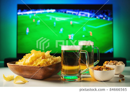 Beer and snacks set on football match tv background. 84666565