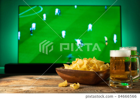 Beer and snacks set on football match tv background. 84666566