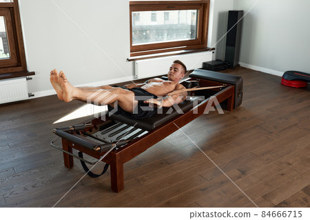 Pilates reformer workout exercises man at gym indoor. 84666715