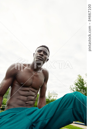 Muscular african man doing push ups in the park. Strong male athlete working out outdoors. Muscular african man doing push ups in the park. Strong male athlete working out outdoors. 84667100