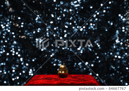 gold christmas ball ornament on red velvet podium on blue sequin background 84667767