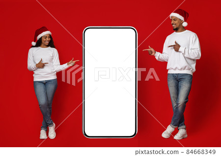 Cheerful black man and woman pointing at huge smartphone, mockup Cheerful black man and woman pointing at huge smartphone, mockup 84668349