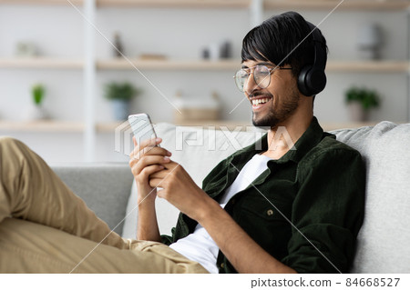Handsome indian guy watching video on smartphone Handsome indian guy watching video on smartphone 84668527