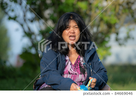 An Asian middle aged woman playing calling a puppy. Soft, blurry background 84669046