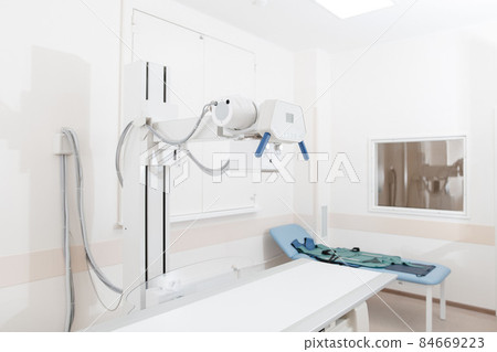 X-ray department in modern hospital. Radiology room with scan machine with empty bed. Technician adjusting an x-ray machine. Scanning chest, heart, lungs in modern clinic office. X-ray department in modern hospital. Radiology room with scan machine with empty bed. Technician adjusting an x-ray machine. Scanning chest, heart, lungs in modern clinic office. 84669223