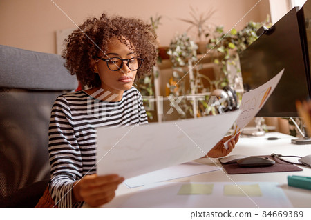 Multiracial woman is studying documents at home Multiracial woman is studying documents at home 84669389