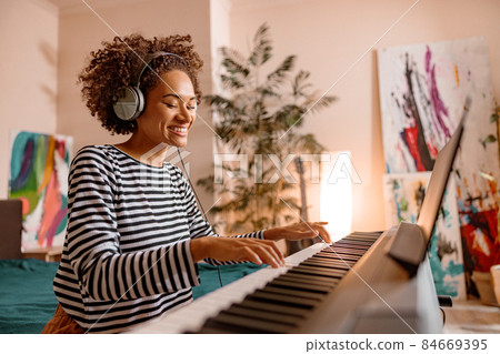 Joyful young woman playing synthesizer at home 84669395