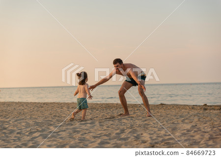 Happy father catch little daughter on beach holding opened arms. Happy father catch little daughter on beach holding opened arms. 84669723